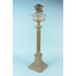 A tall brass column oil lamp with glass reserve,