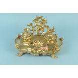 A late 19th Century continental gilt brass inkstand of Rococo design with two lidded inkwells,
