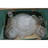 A box of various cut crystal glass items including a large plate, lidded biscuit barrel, cruet,