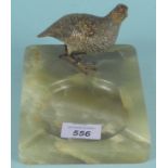 An onyx ashtray surmounted by a cold painted bronze figure of a partridge