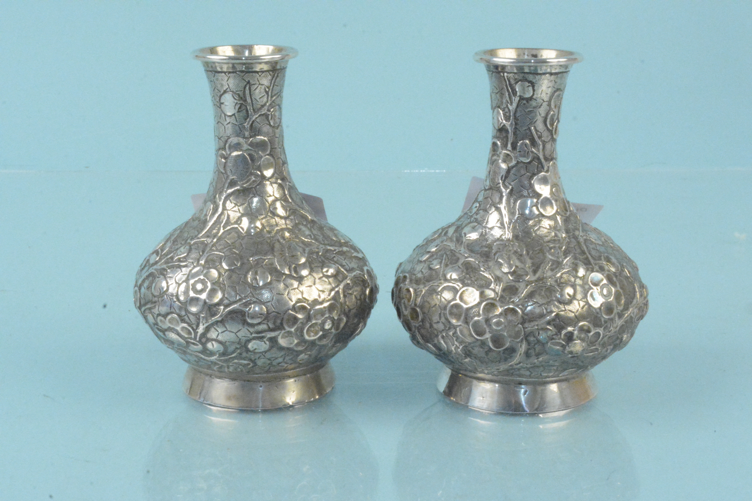 A pair of Chinese silver bud vases with embossed floral decoration,