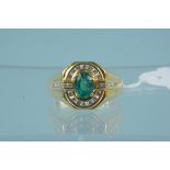 An unmarked gold ring set with emerald and diamonds,