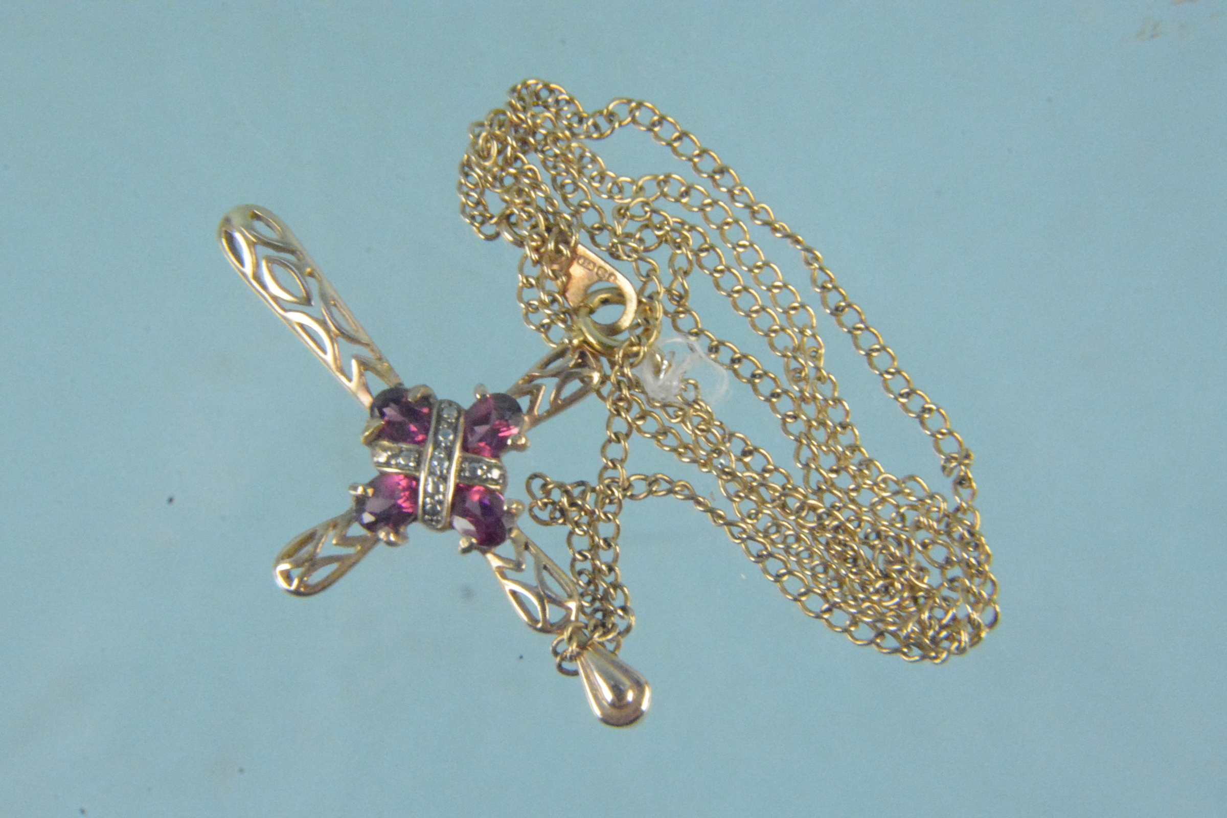 A 9ct gold necklace with pierced pink stone and diamond set cross pendant