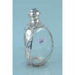 A shaped glass decanter with white metal overlay and lid,