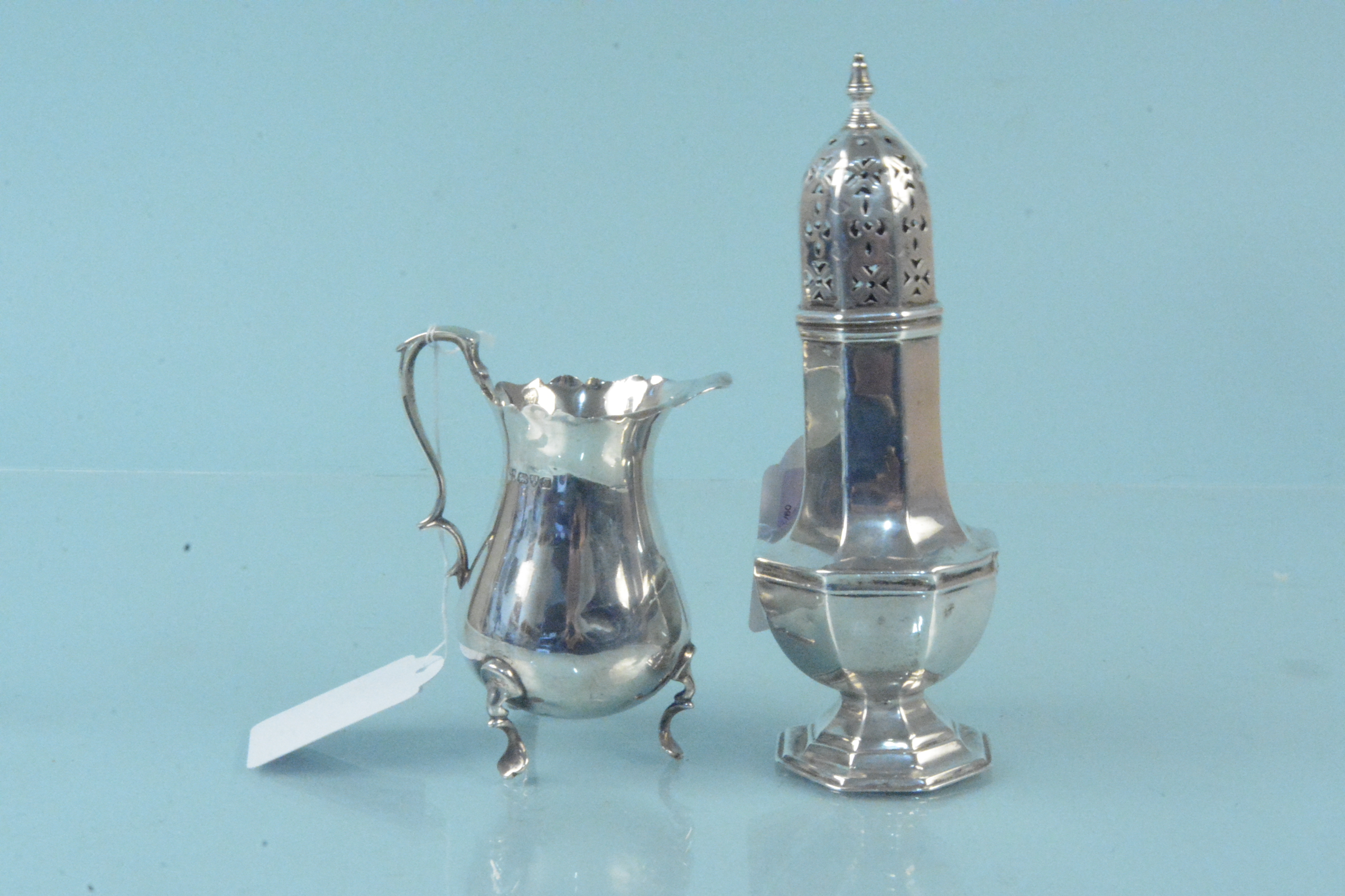 A silver sugar sifter (as found) plus a silver cream jug (as found), both hallmarked Chester 1906,