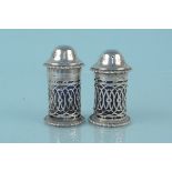 A near pair of silver pepperettes with pierced decoration and blue glass liners,