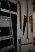 Items on Wall; Two Saws, Four Walking Sticks, Draining Rods, and a Rake