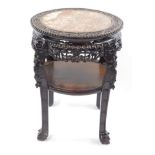 A late 19thC Chinese circular hardwood urn stand, the foliate carved and marble inset top, raised on