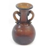 An antique brown glass Roman style vessel, with two handles, 15cm high.