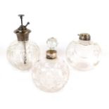 Three cut glass dressing table bottles, each with silver rim or top, comprising an atomiser,
