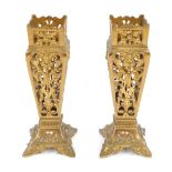 A pair of Victorian brass vase holders, each cast and pierced with scrolls and masks, of square