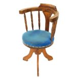 An early 20thC oak swivel chair, upholstered in over stuffed blue draylon, raised on three solid