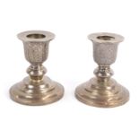 A pair of Thai silver squat pricket candlesticks, the tops with trailing leaf design, on stepped