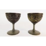 A pair of Chinese coconut beakers, each with pewter lined interior and stemmed foot, carved to the