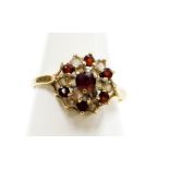 A 9ct gold dress ring, formed as a cluster set with layers of garnets and czs, on a raised basket,