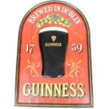 A wooden Guinness advertising sign, of arched form, Brewed In Dublin 1759, depicting a raised