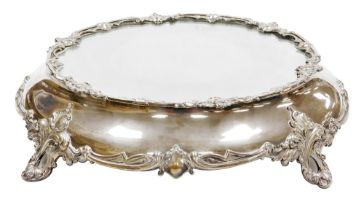 A Victorian silver plated wedding cake stand, with a mirrored top, the base decorated with vacant