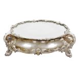 A Victorian silver plated wedding cake stand, with a mirrored top, the base decorated with vacant