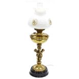 A brass oil lamp type electric table lamp, cast with a figural support, with clear glass chimney and