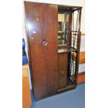 An oak dressing cabinet, with a sliding panel revealing a single wardrobe, beside a recess