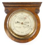 An Edwardian oak wall barometer, in circular case with 15cm diameter dial in brass casing, 28cm high