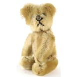 An Edwardian miniature Schuco Teddy bear, with articulated head, rotating on an axis with hand turni