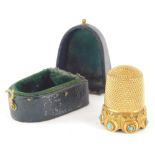 A gilt metal thimble, engine turned and set with turquoise, unmarked, 2cm high, partially cased. (AF