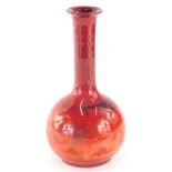 An early 20thC Bernard Moore flambe bottle shaped vase, decorated with dragons, on a circular foot,