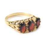 A ladies 9ct gold garnet dress ring, with three claw set faceted cut stones on a pierced shank decor