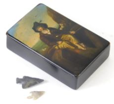 A 19thC papier mache snuff box, decorated with a figure on a shoreline, 9cm wide and two axe heads,