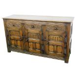 An Elizabethan style oak sideboard, with three carved frieze drawers over panelled doors, with fast