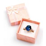 A dress ring, set with an oval cut blue topaz in a four claw setting, with v splayed shoulders each