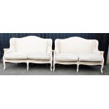 A pair of cream painted faux bamboo framed two seater sofas, upholstered in striped and patterned fa