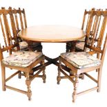 An Ercol dark elm oval extending dining table, raised on baluster turned columns united by an x fram