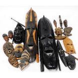 A group of treen tribal masks, of various sizes, a fishing spear with an arrowhead and wooden handle