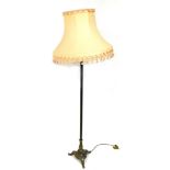 An early 20thC brass standard lamp, with a peach coloured shade, 157cm high.