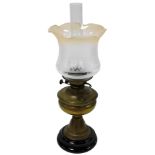 An early 20thC brass oil lamp, on a black pottery socle, with chimney and frosted and etched glass s