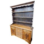 A Victorian oak dresser, the out swept pediment over three shelf plate rack, above five central draw