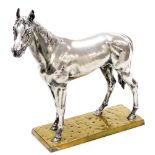 A mid 20thC equestrian sculpture, possibly previously silver plated, on a hammered brass base, 32cm
