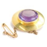 An oval brooch, set with amethyst coloured stone with plain pin back, marked 15ct, 3cm wide, 8.6g.