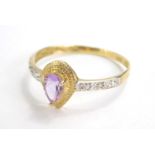 A ladies dress ring, claw set with a central amethyst coloured stone, flanked by small diamonds to e