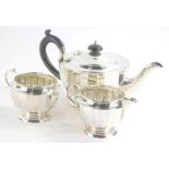 A George VI silver three piece tea service, of ribbed form comprising compressed circular teapot wit