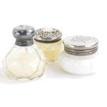 Three miniature dressing table jars, one 3cm high, with cut glass body and repousse decorated silver