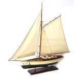 A wooden boat model, with single mast on a cream and black base, on a rectangular wooden frame, 71cm