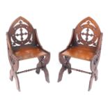 A pair of Victorian oak Gothic hall chairs, each with shield carved back, on strut supports and outs
