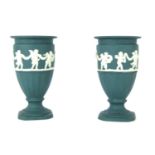 A pair of Wedgwood turquoise Jasperware miniature urns, each with a border of cherubs, on stepped ba