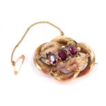 A Victorian oval brooch, with three central garnets, and two vine leaves with interlinked hammered d