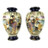 A pair of Japanese Satsuma vases, with a cream panel depicting Geishas, each on a royal blue ground