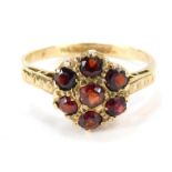 A 9ct gold garnet cluster ring, set with seven garnet stones in a patterned ring head, on hatch desi