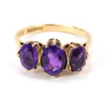 A 9ct gold three stone amethyst dress ring, with three oval amethyst, each in claw setting on pierce